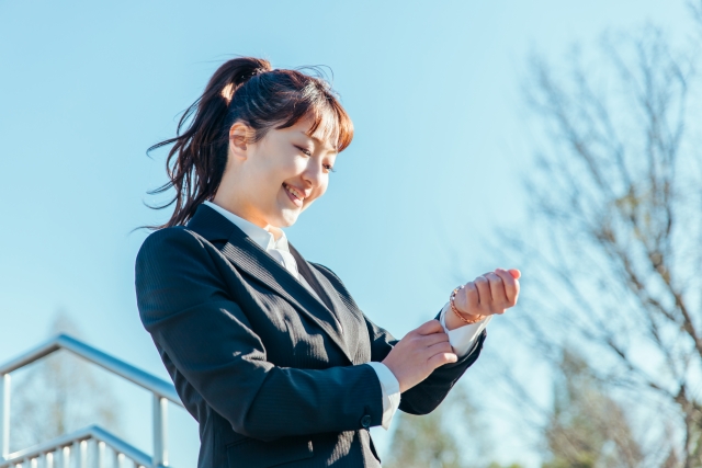 腕時計を見るビジネスウーマン（笑顔）